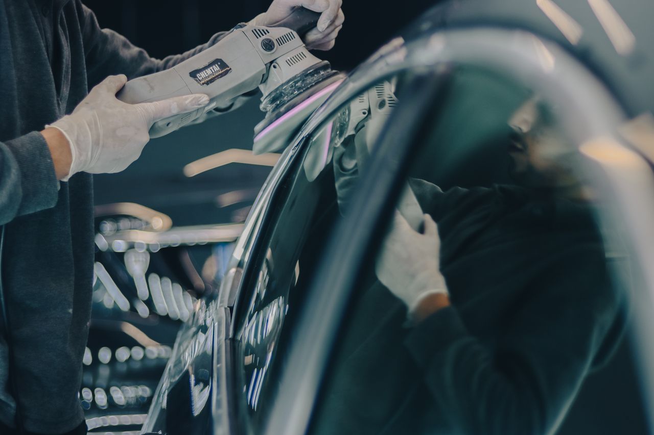 Mastering the First Impression: Your intriguing post title goes here Close-up of car detailing process with polishing machine and reflective surface in workshop.
