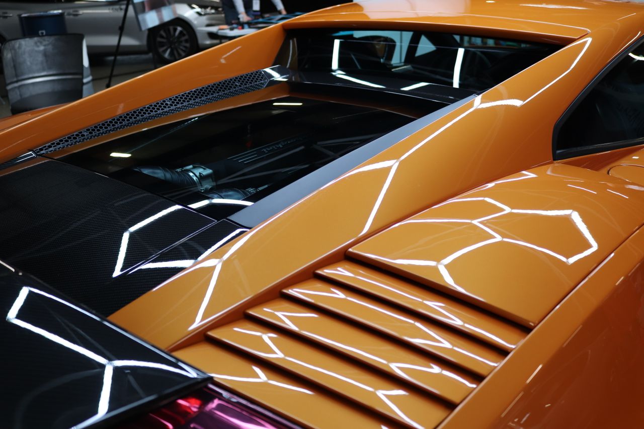 Detailed image of a yellow sports car engine area with reflective surfaces and sleek design.